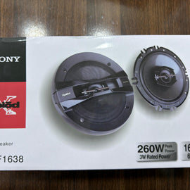 A boxed pair of Soony car speakers on a white retail package, photographed on a wooden tabletop. The box shows product photos of the speakers, technical text including 260W and 3W Ralled Power, and the Soony brand name.